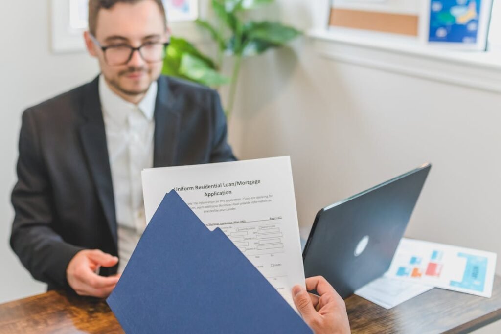 Small business owner reviewing a loan application document with a laptop on the desk