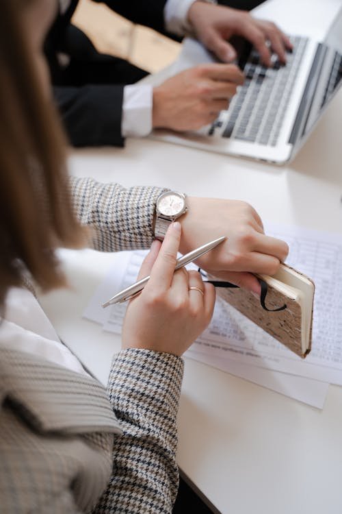 Woman checking watch while working on laptop - time tracking for small business