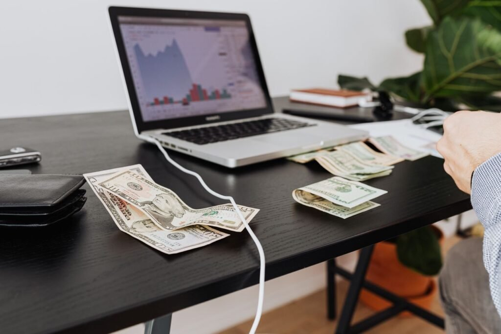 Workspace with cash, laptop, and financial charts used for small business cash flow forecasting