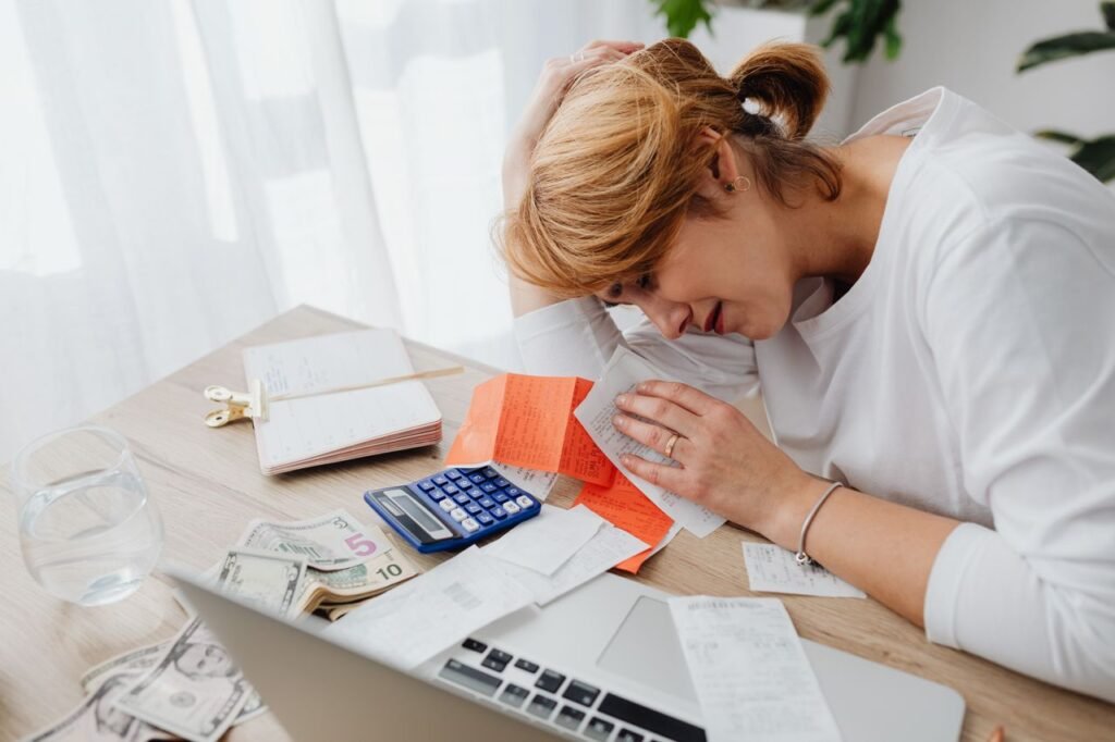 Business owner at a desk surrounded by piles of receipts and bills while sorting expenses