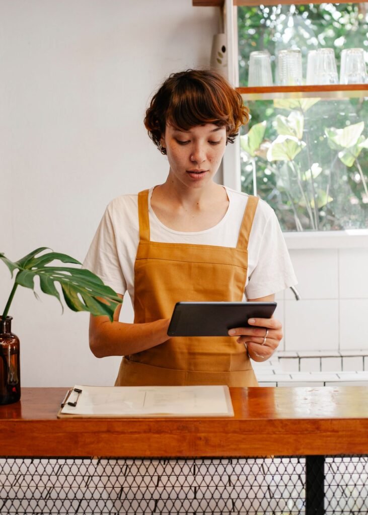 Cafe employee using a tablet at the counter to manage shifts and payroll