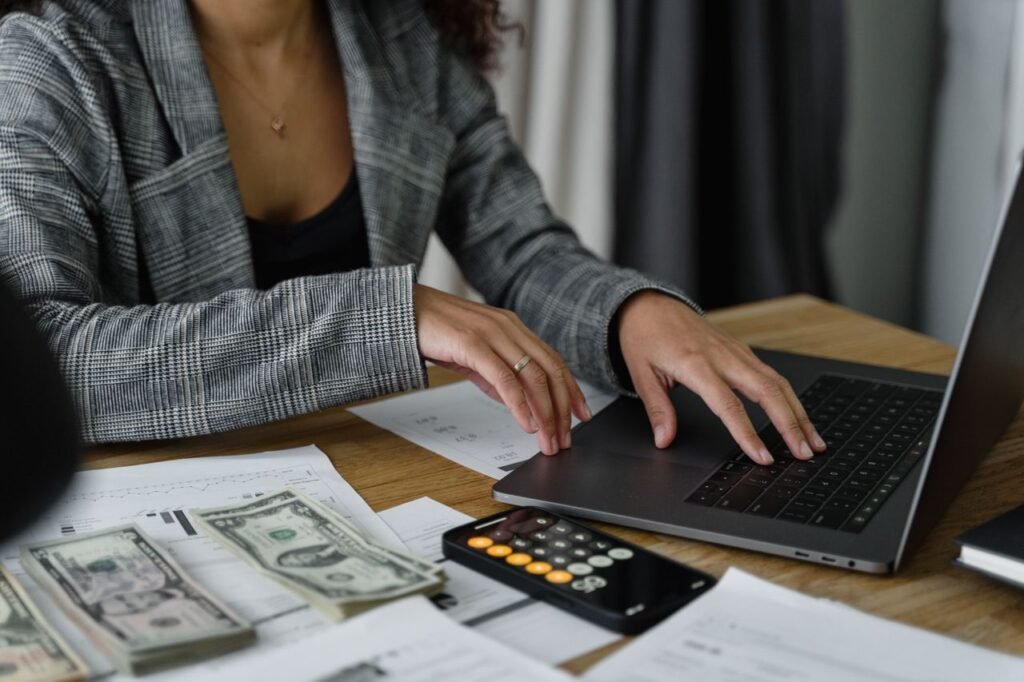 Businesswoman comparing payroll costs with a laptop and calculator at her desk