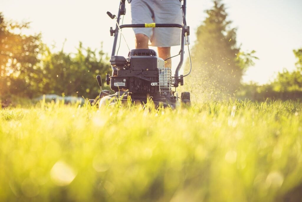 Landscaping professional mowing a lawn with a gas-powered mower on a sunny day