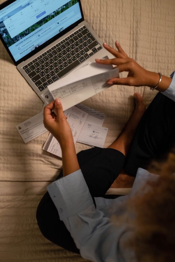 Business owner holding checks while paying bills online with a laptop