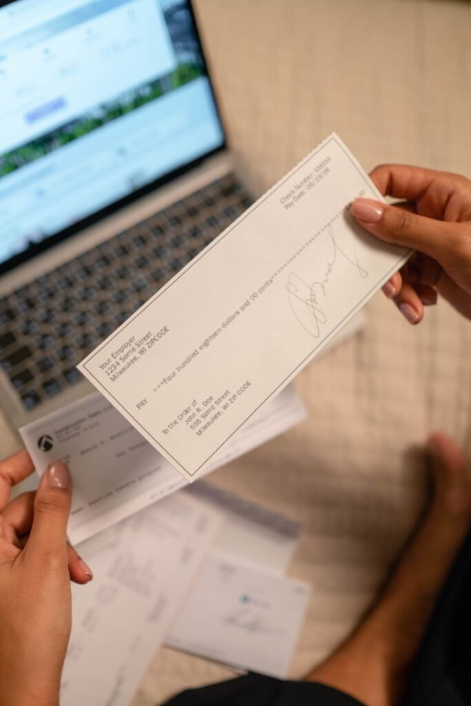 Business owner holding a check over a laptop while paying themselves from their LLC