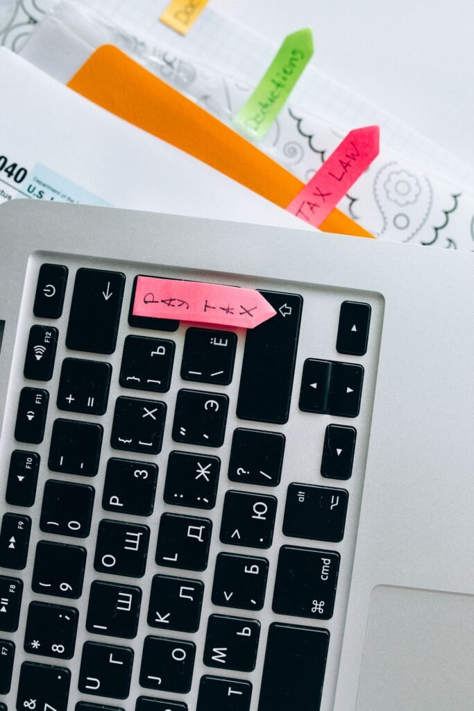 Laptop displaying tax documents with sticky notes on a desk during small business tax preparation
