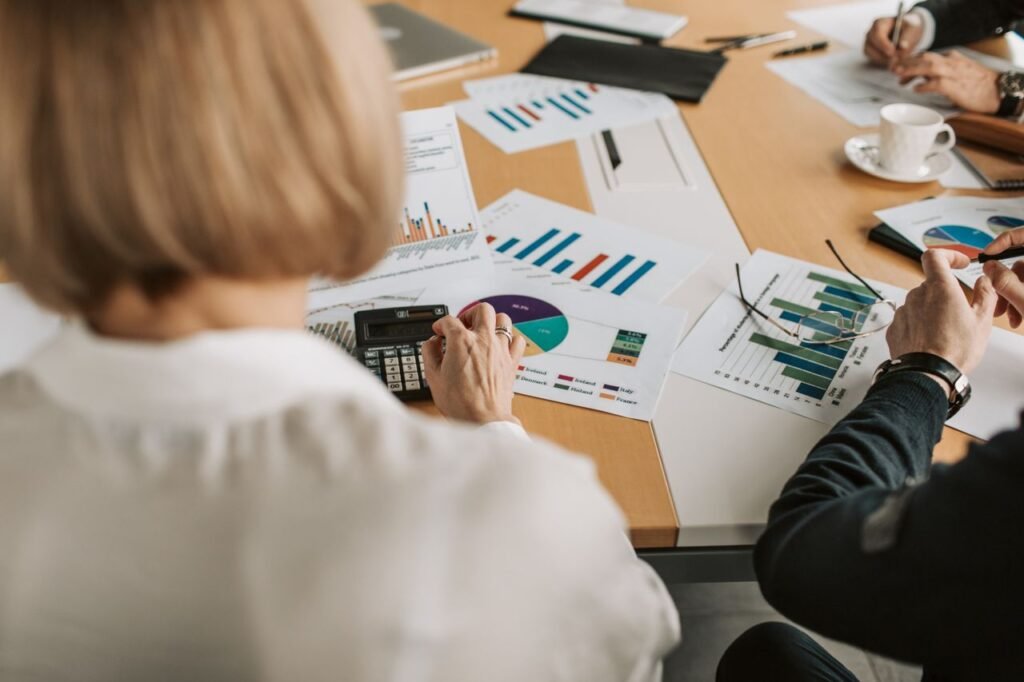 Overhead view of finance professionals reviewing charts and using calculators in a corporate office