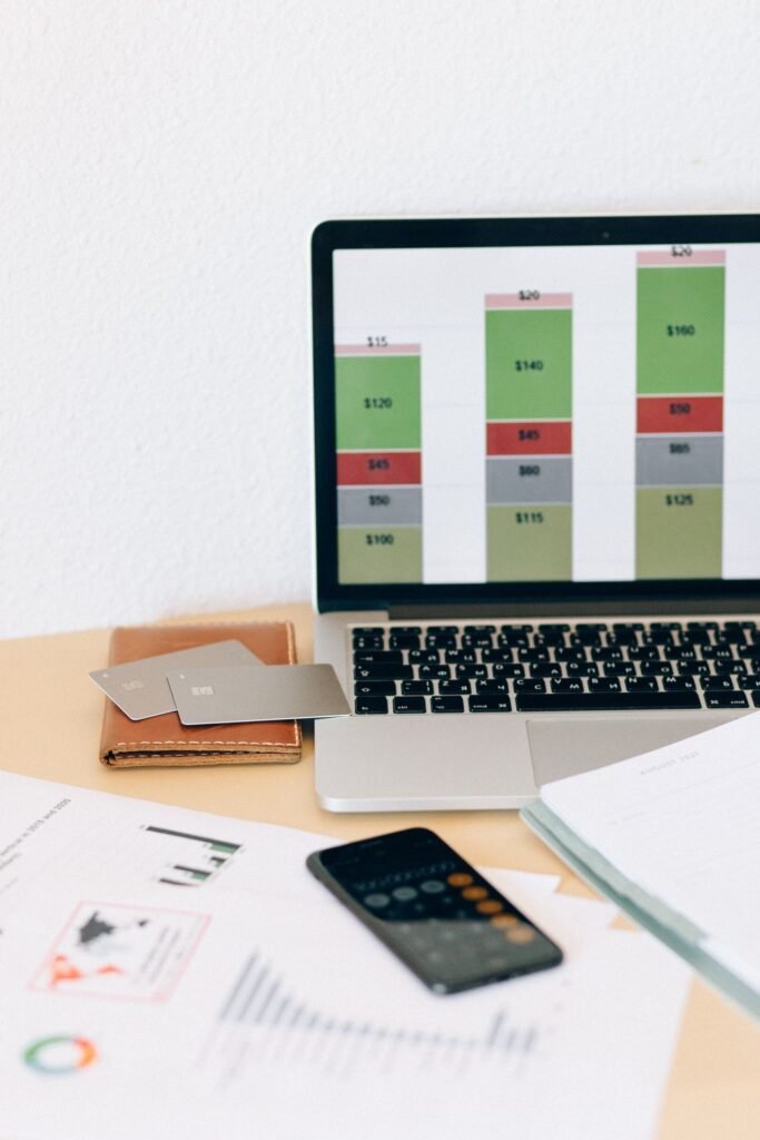 Laptop displaying financial charts with documents and bank cards on a desk, representing online business banking