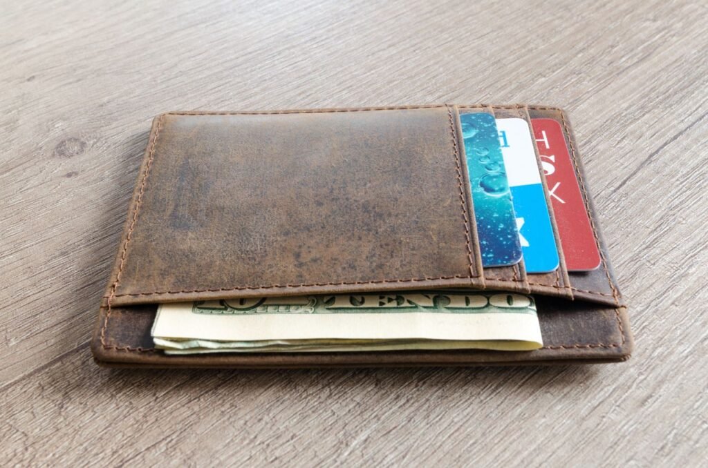 Leather wallet with cash and credit cards on a wooden surface